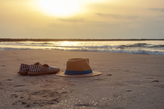Panama hat and espadrilles on sandy beach by the sea