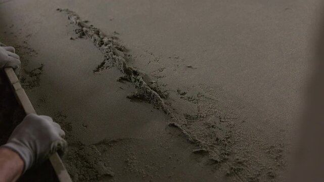 Leveling cement floor screed with straightedge during finishing