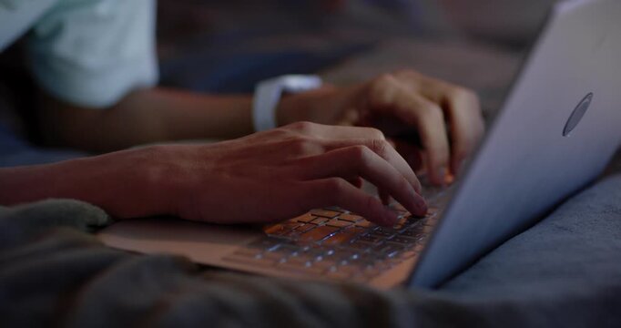 Hands are shifting from rest and typing on laptop on bed, wristwatch glowing for work