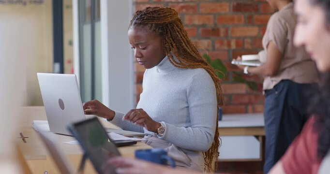 Woman positioning laptop, consulting notebook and typing at counter for work, copy space
