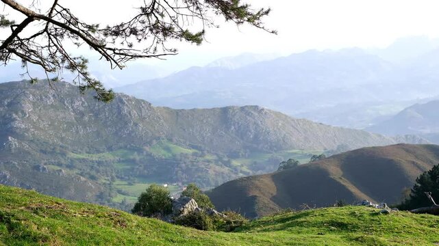 A breathtaking panoramic view of the lush, rolling green hills and majestic mountain ranges in Parres, Asturias, Spain.