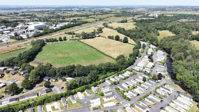 Aerial drone 4K clip showing caravans placed across rolling countryside vegetation under warm daylight Wales