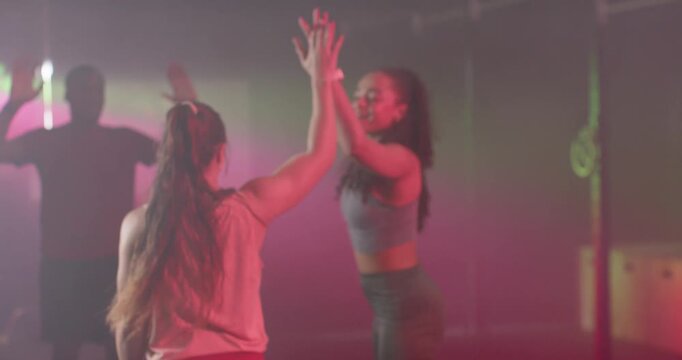 Workout partners following lead cue, high-fiving and syncing arms at studio with wrist tracker