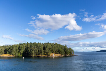 Fototapeta premium Tranquil Forested Island With Lighthouse Overlooking Calm Ocean Under Blue Sky, Gulf Islands, British Columbia