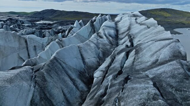 Cinematic aerial flight above the spectacular glacier front of Fjalls&aacute;rl&oacute;n Glacier Lagoon in Iceland, revealing deep crevasses, blue glacial ice and the dramatic landscape of Vatnaj&ouml;kull.