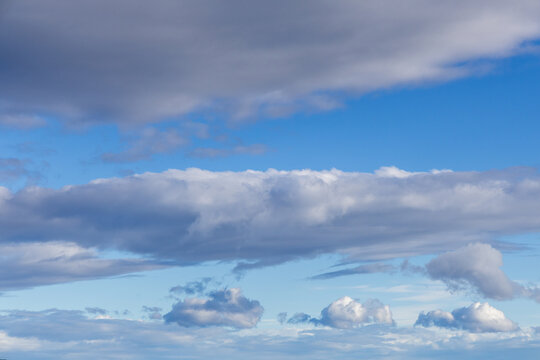 Layered Blue Sky Cloudscape With Soft White and Gray Clouds Over Open Horizon