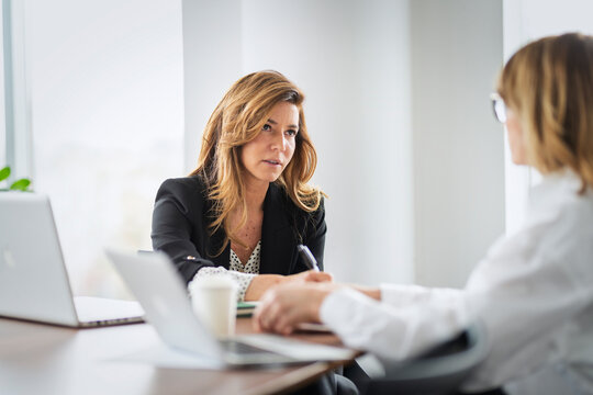 Two professional women collaborating on a project in office