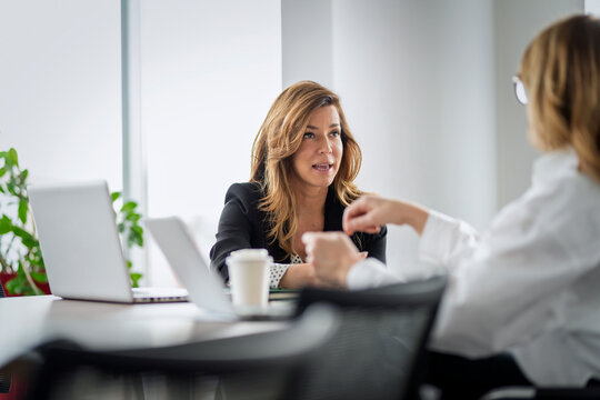 Two professional women collaborating on a project in office