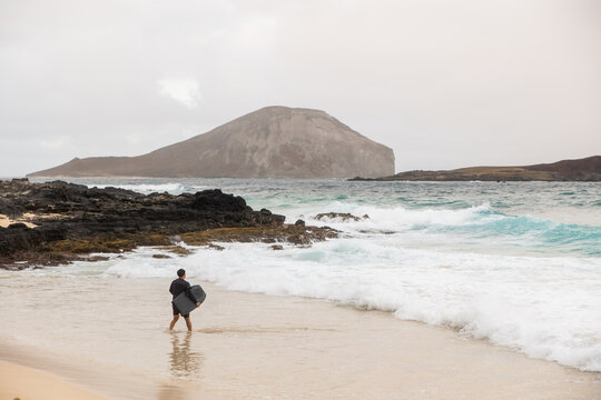 Man walking along Makapuu Beach with Rabbit Island in the background, Oahu