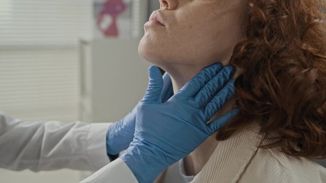 Hands of doctor wearing blue gloves palpating neck of young Caucasian female patient during medical examination. Video is ideal for healthcare services and clinical diagnostics marketing
