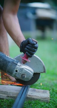 Person wearing safety glove operating angle grinder cutting metal creating bright sparks