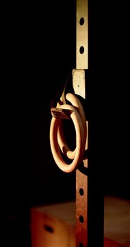 Vertical video: Rings are swaying from subtle shifts on metal rack as warm light is casting shadow