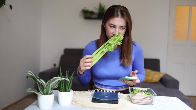 Calorie counting becomes a daily habit as a woman checks her meal plan before eating celery staying committed to weight loss and strict nutrition goals
