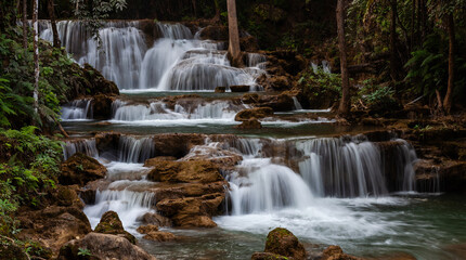 Huay Mae Khamin Waterfalls cascading through lush jungle in Kanchanaburi, Thailand. Tropical forest surrounds the flowing water, creating a scenic natural river landscape. © Eugene Ga