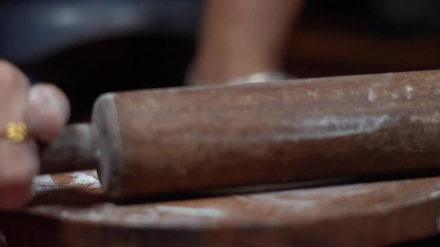 Indian Homemaker Preparing Flatbread by Rolling Raw Atta Dough with Wooden Belan. Baker Shaping Round Flat Dough Sheet with Rolling Pin for Traditional Indian Puri.