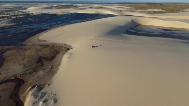 High drone view of ATVs crossing dunes and lagoons in Brazil