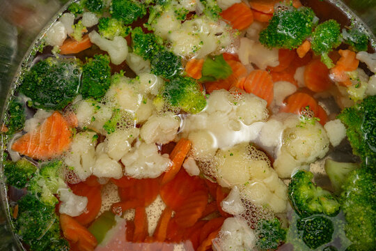Fresh vegetables cooking in boiling water with bubbles on a stove in a kitchen
