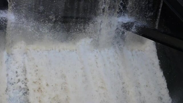 close-up of water rushing through a tainter gate inside a controlled spillway at a low-head dam with sound. dynamic video. floodgate metaphor