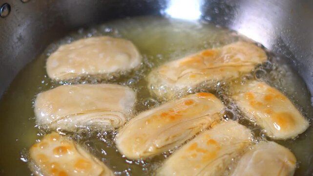 Deep Frying Traditional Puri Famous Pheni Khaja in Hot Oil Kadhai. Crispy Odia Sweet Feni Frying in Boiling Oil for Jagannath Temple Prasad. Pheni Being Cooked in Deep Fryer for Odisha Festival.