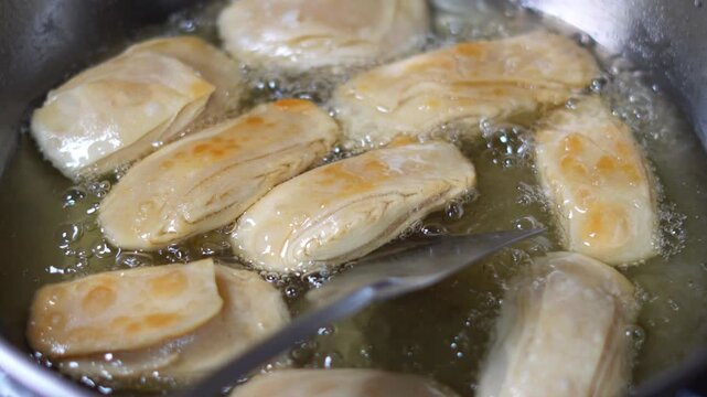 Deep Fried Food Cooking, Flipping Crispy Indian Sweet Khaja Pastry in Hot Oil. Close Up of Frying Traditional Odia Sweet Khaja in Boiling Oil with Spatula. Indian Sweet Preparation. Puri Famous Khaja.