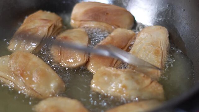 Deep Frying Crispy Indian Sweet Khaja Pastry in Hot Oil in Kadhai Pan. Close Up of Frying Traditional Odia Sweet Khaja in Boiling Oil in Indian Kitchen.