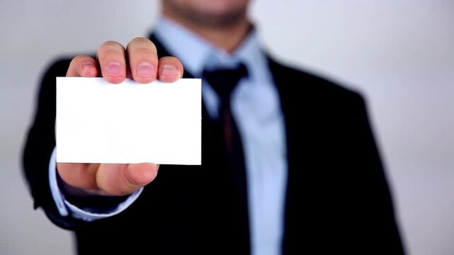 Businessman in a suit holding out a blank white business card with copy space, ready for customization or contact information