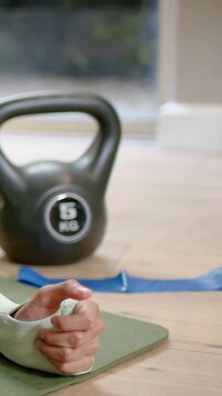 Vertical video: Lowering onto arms, hijabi holding plank at home for form near 5kg bell, copy space