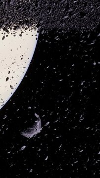 An asteroid moves through space near a large planet. The planet has glowing rings made of dust and rock. The dark background shows the vastness of the universe.