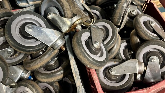Close-up of shopping cart caster wheels stacked in plastic crates, representing supermarket equipment, retail maintenance, logistics, spare parts, repair services and commercial operations
