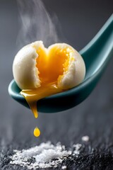Fototapeta premium Soft-boiled egg yolk dripping from teal ceramic spoon with rising steam