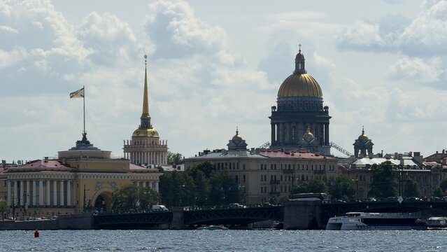 The golden dome of St. Isaac's Cathedral and the Admiralty spire tower over the city skyline along the Neva river in St. Petersburg.