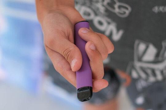 Disposable electronic cigarettes in a teenager's hands.