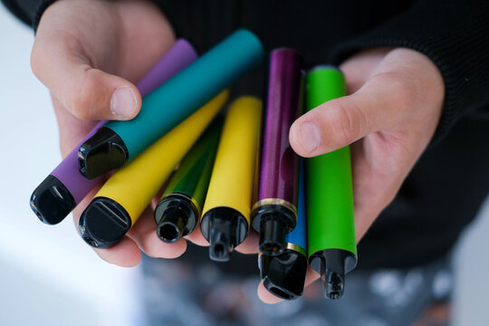 A child is holding many colorful vapes. A dangerous addiction.=