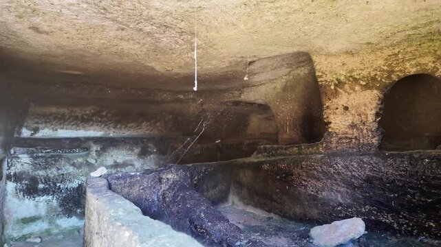 Salina, Malta - the interior of an ancient Paleo-Christian catacomb reveals rock-cut burial recesses carved into the stone, designed to hold two bodies, with cobwebs and natural weathering marking the