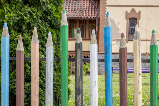 Colorful wooden pencil fence in front of a building during daytime