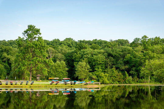 Morning reflections on Hopewell Lake at French Creek State Park with colorful canoes and kayaks along the shoreline.