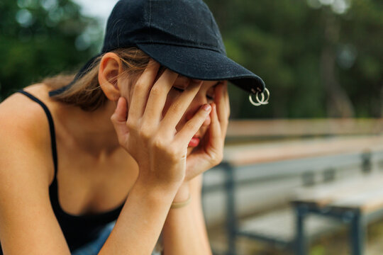 Close up of a crying teenage girl covering her face with hands.