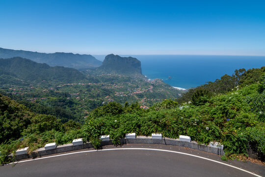 Beautiful coastal landscape of Madeira with blooming agapanthus flowers, green mountains and blue ocean sky