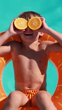 A happy child is having fun on the summer vacation. A kid is swimming in the pool. Vertical video. Slow motion