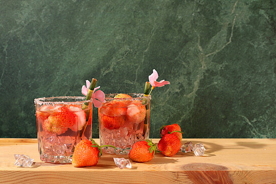 Festive alcoholic cocktail, pink martini in glasses on a bright background with strawberries, summer bar concept, alcoholic drinks at a party, restaurant and cafe advertising, modern still life