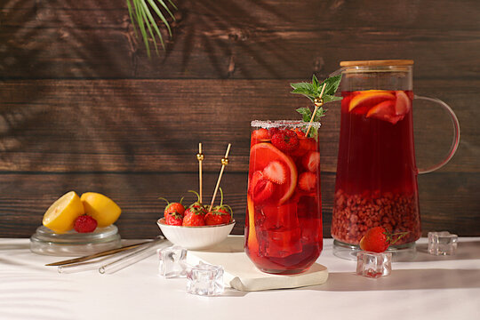 Strawberry Iced Tea or Mint Lemon Cocktail is a refreshing summer drink recipe. Glasses with berry fruit lemonade on a light concrete table, detox diet and weight loss concept, restaurant menu.