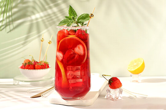 Strawberry Iced Tea or Mint Lemon Cocktail is a refreshing summer drink recipe. Glasses with berry fruit lemonade on a light concrete table, detox diet and weight loss concept, restaurant menu.
