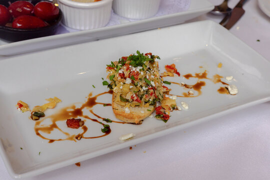 Artichoke bruschetta appetizer with balsamic glaze on white plate