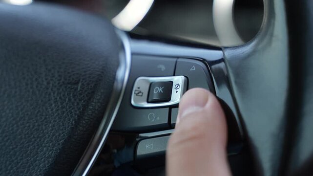 Close Up of Driver Pressing Steering Wheel Control Button in Car