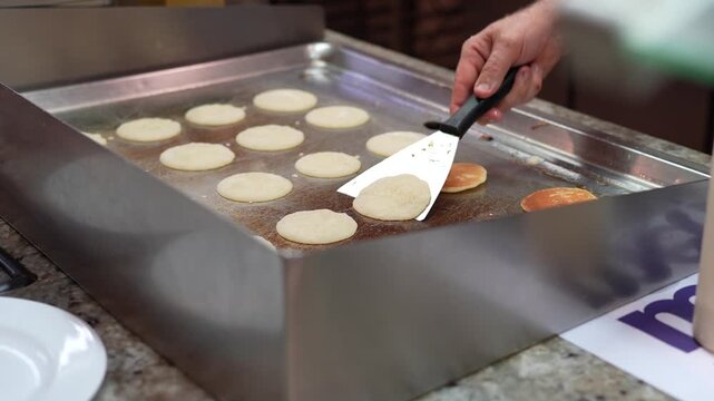 Chef Cooking Mini Pancakes on Hot Griddle Close Up