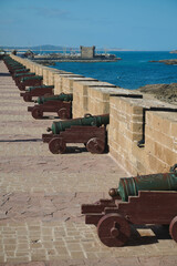 Fototapeta premium Row of historic cannons along Essaouira medina sea wall overlooking harbor and Atlantic coast in Morocco