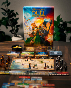 Portrait product photograph of Lord of the Rings Duel for Middle Earth game box and components on wooden table with dramatic lighting designed by Antoine Bauza and Bruno Cathala