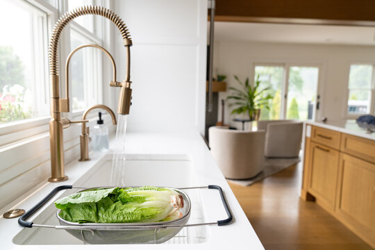 Modern kitchen with romaine lettuce washing in sink colander