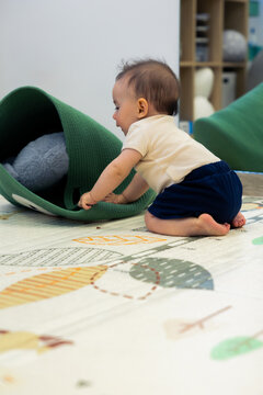Baby exploring green tunnel toy on play mat