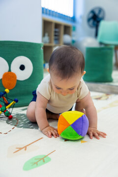 Baby playing with colorful toy on playmat at home